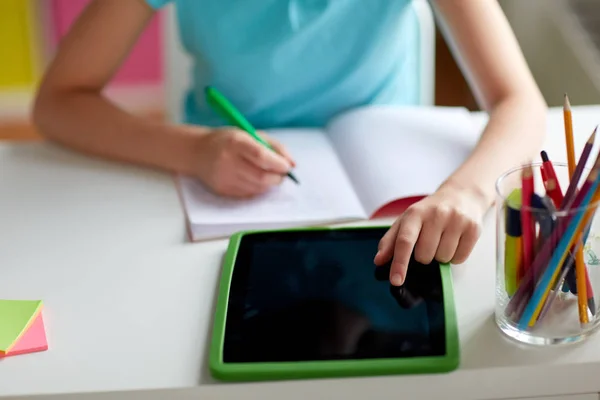 Chica con la escritura de la PC tableta a la libreta en casa — Foto de Stock