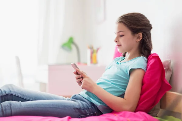 Smiling girl texting on smartphone at home — Stock Photo, Image