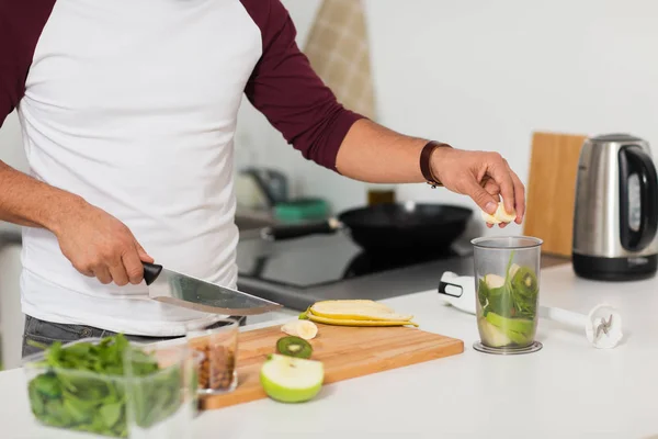 Человек с блендером и фруктами приготовления пищи на домашней кухне — стоковое фото