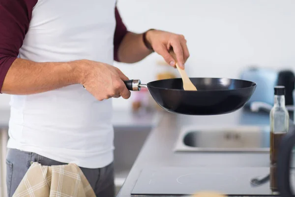 Man with frying pan cooking food at home kitchen — Stock Photo, Image