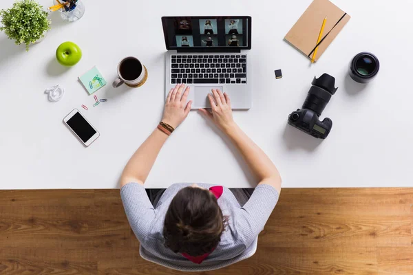 Donna con macchina fotografica che lavora su computer portatile a tavola — Foto Stock