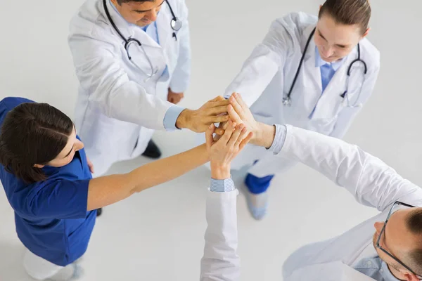 Group of doctors making high five at hospital — Stock Photo, Image