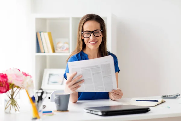 Mujer feliz en gafas leyendo el periódico en la oficina — Foto de Stock