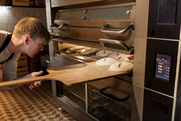 Bäcker legt Teig in Brotbackofen beim Bäcker — Stockfoto
