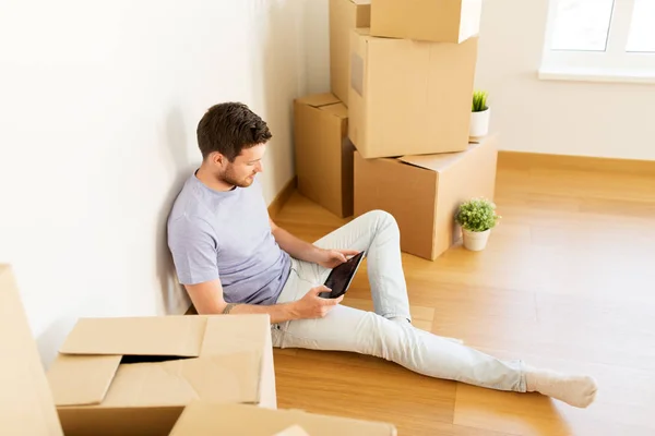 Man with tablet pc and boxes moving to new home — Stock Photo, Image