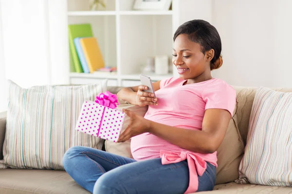 Donna africana incinta con smartphone e regalo — Foto Stock