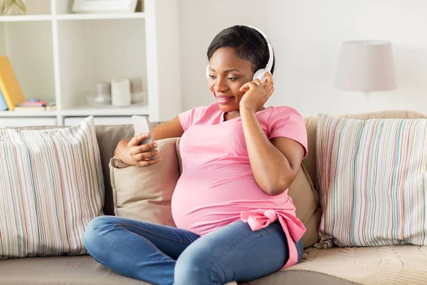 Hamile kadın kulaklık ile smartphone — Stok fotoğraf