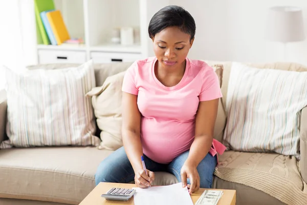 Pregnant woman with bills and money at home — Stock Photo, Image