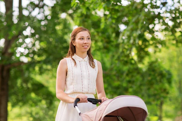 Ibu bahagia dengan anak di kereta bayi di taman musim panas — Stok Foto