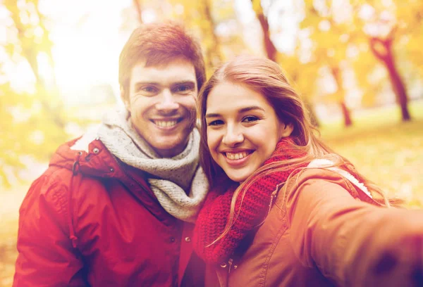 Gelukkige jonge paar nemen selfie in herfst park — Stockfoto