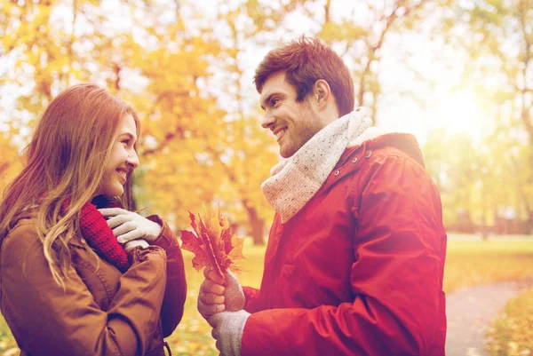 Pareja feliz con hojas de arce en el parque de otoño —  Fotos de Stock