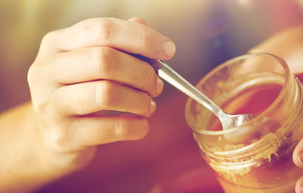 Close up of woman hands with honey and spoon — Stock Photo, Image