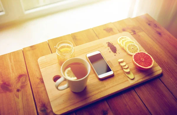 Smartphone com xícara de chá limão, mel e gengibre — Fotografia de Stock