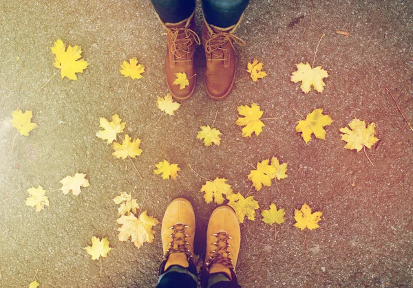 Ζευγάρι πόδια σε μπότες και φθινοπωρινά φύλλα — Φωτογραφία Αρχείου