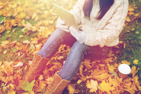 Vrouw met tablet pc en koffie in de herfst park — Stockfoto