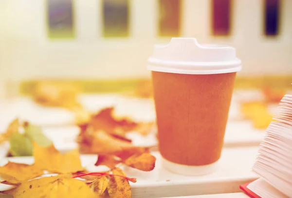 Kaffedrikke i papirkop på bænk i efterårsparken - Stock-foto