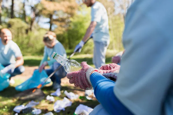 Vrijwilliger met vuilnis zak en fles reiniging gebied — Stockfoto