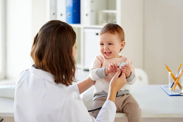 Счастливый врач или педиатр с ребенком в клинике — стоковое фото
