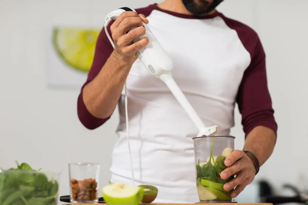 Hombre con licuadora y cocina de frutas en la cocina casera —  Fotos de Stock