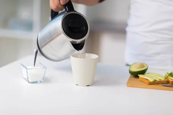 Hombre con hervidor de agua haciendo té para el desayuno en casa — Foto de Stock