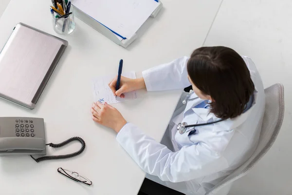Doctor scriind prescripție la masă — Fotografie, imagine de stoc