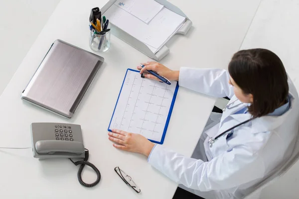 Arzt mit Kardiogramm sitzt am Tisch — Stockfoto