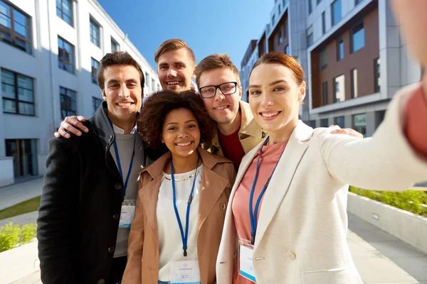 Team with conference badges taking selfie in city — Stock Photo, Image
