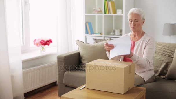 Ευτυχής ανώτερος γυναίκα άνοιγμα δέματος κουτί στο σπίτι — Αρχείο Βίντεο