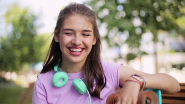 Счастливая девочка-подросток с наушниками и лонгбордом — стоковое видео