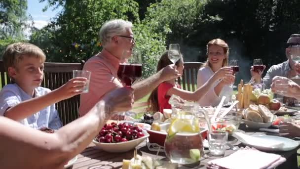 Ευτυχισμένη οικογένεια έχοντας δείπνο ή καλοκαιρινό πάρτι στον κήπο — Αρχείο Βίντεο