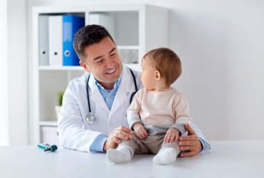 happy doctor or pediatrician with baby at clinic clipart