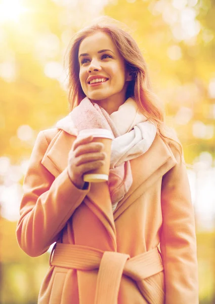 Щаслива молода жінка п'є каву в осінньому парку — стокове фото