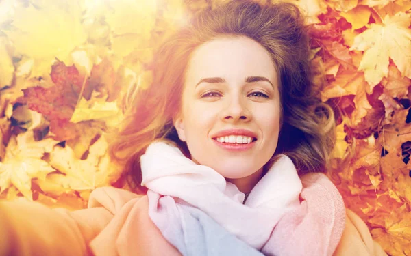 Hermosa mujer feliz acostada en hojas de otoño — Foto de Stock