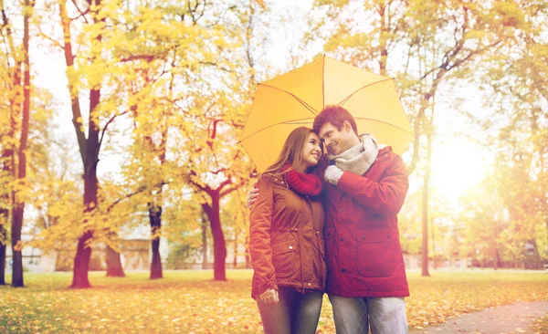 Usmívající se pár s deštníkem v podzimním parku — Stock fotografie