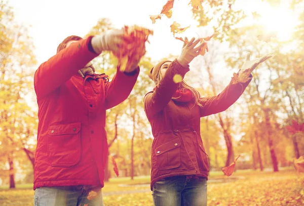 Heureux jeune couple jetant des feuilles d'automne dans le parc — Photo