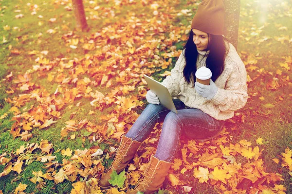 Donna con tablet pc e caffè nel parco autunnale — Foto Stock