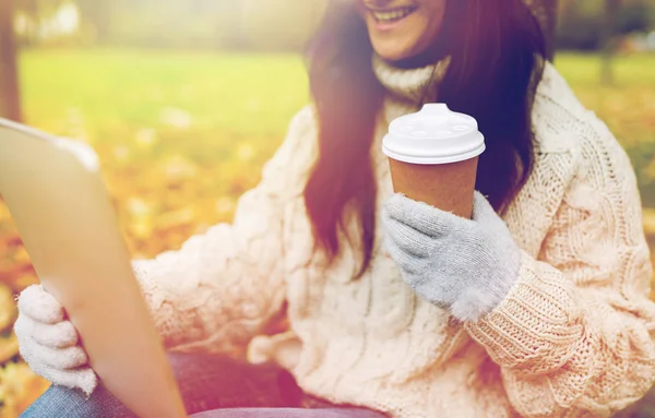 Mujer con tablet PC y taza de café en el parque de otoño — Foto de Stock