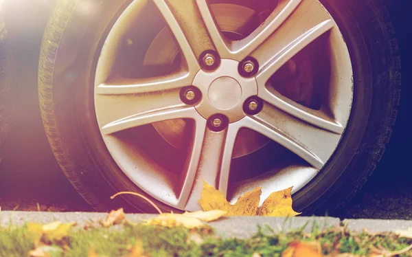 Perto da roda do carro e folhas de outono — Fotografia de Stock