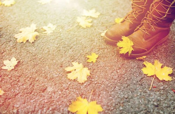 Piedi femminili in stivali e foglie autunnali — Foto Stock