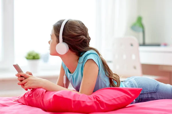 Flicka i hörlurar lyssnar på musik hemma — Stockfoto