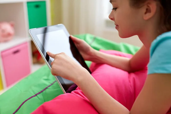 Улыбающаяся девушка с планшетным компьютером, лежащая дома на кровати — стоковое фото