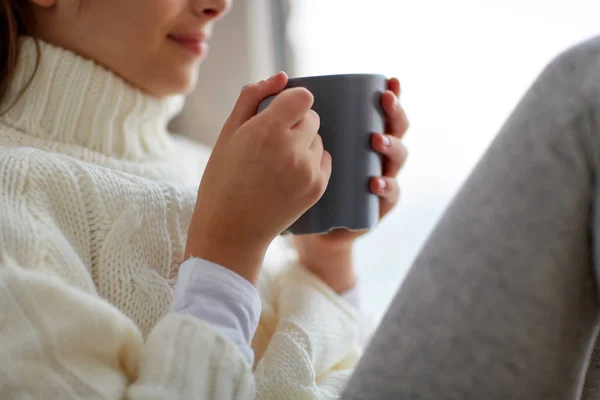 自宅ウィンドウで座って茶マグカップを持つ少女 — ストック写真