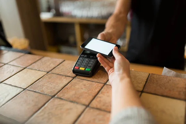 Hands with payment terminal and smartphone at bar — Stock Photo, Image