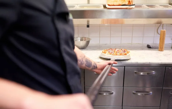 Cocinar o panadero con pizza en la cáscara en la pizzería —  Fotos de Stock