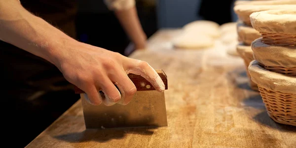 Baker portionering degen med bänk cutter på bageri — Stockfoto