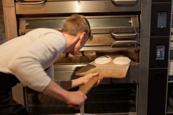 Boulanger mettre la pâte dans le four à pain à la boulangerie — Photo