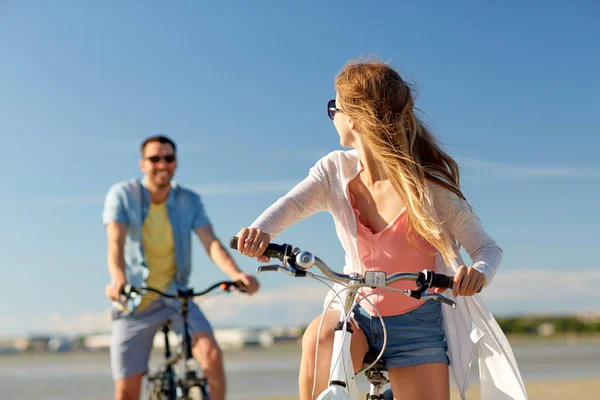 Feliz casal jovem andar de bicicleta à beira-mar — Fotografia de Stock