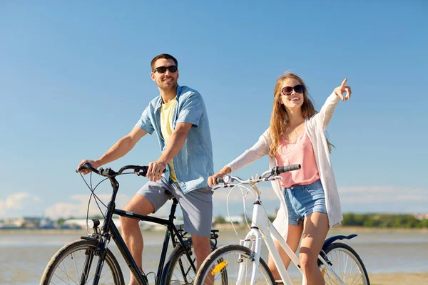 海辺で自転車に乗って幸せな若いカップル — ストック写真