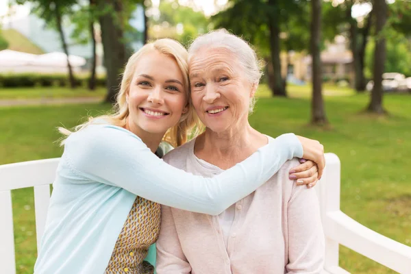 Tochter mit älterer Mutter auf Parkbank umarmt — Stockfoto