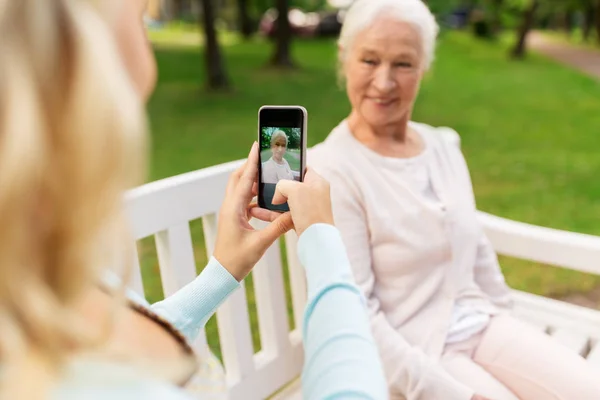 Дочь фотографирует старшую мать по смартфону — стоковое фото